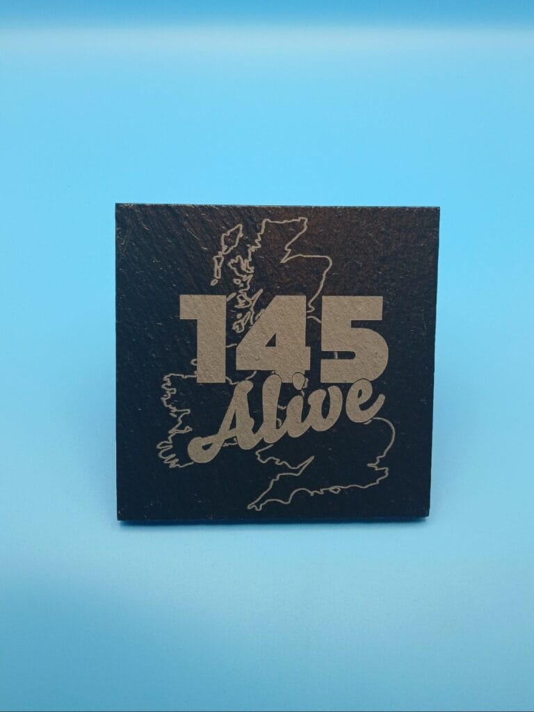 Close-up of 145 Alive design engraved on natural slate coaster